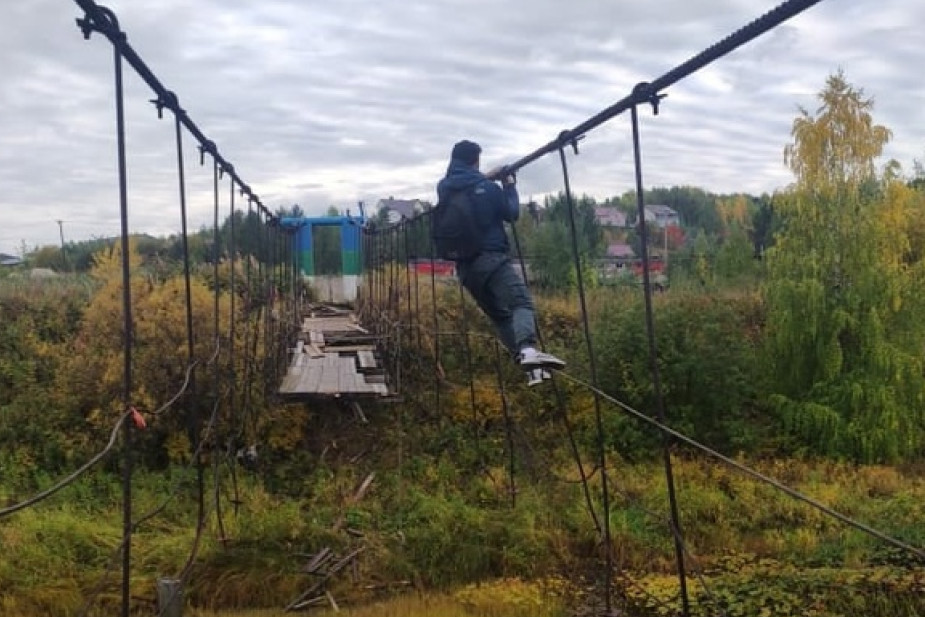 Мальчик переходит реку через веревки, на которых висит мост 