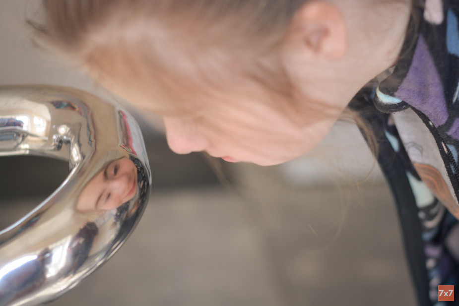 Даша рассматривает свое отражение в металлическом поручне